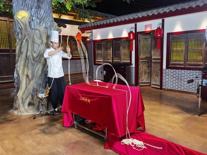 (แฟ้มภาพซินหัว : เชฟอาวุโสโชว์ทักษะการยืดแป้งบะหมี่ด้วยมือในเมืองไท่หยวน มณฑลซานซีทางตอนเหนือของจีน วันที่ 2 ส.ค. 2022)