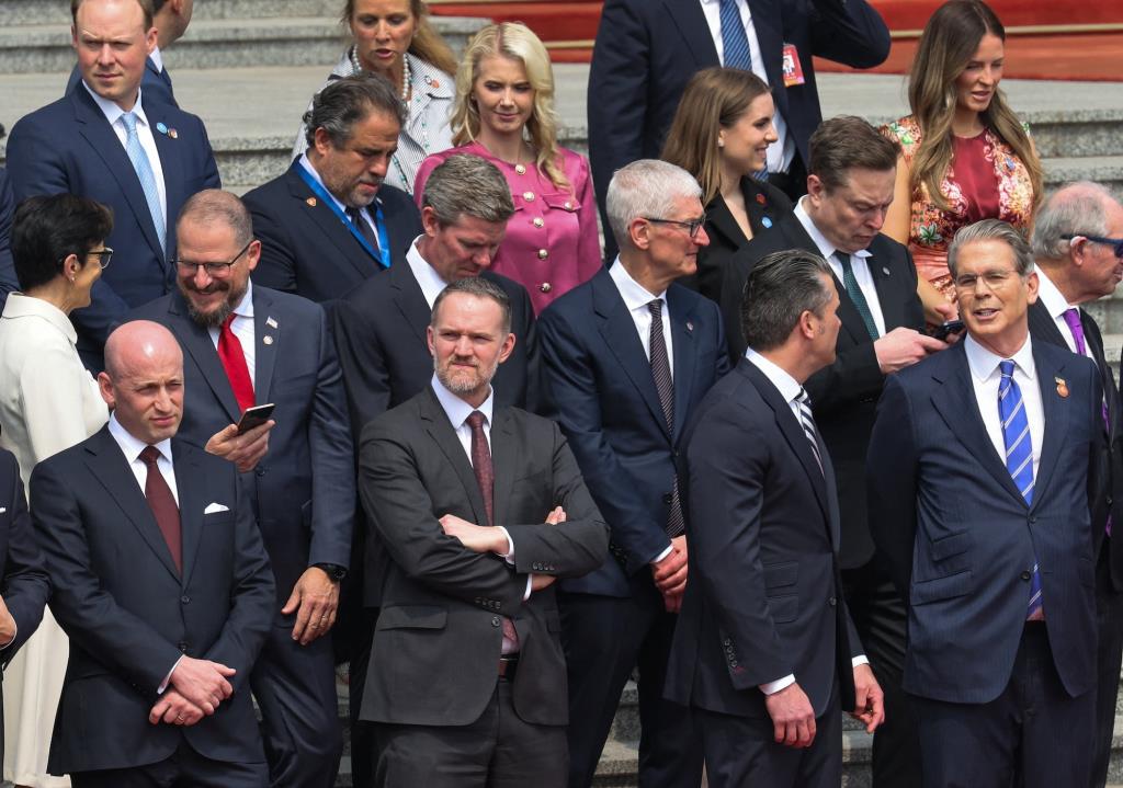 สตีเฟน มิลเลอร์ รองหัวหน้าคณะเจ้าหน้าที่ทำเนียบขาวสหรัฐฯ, เจมีสัน กรีเออร์ ผู้แทนการค้าสหรัฐฯ, พีท เฮกเซธ รัฐมนตรีว่าการกระทรวงกลาโหมสหรัฐฯ, สก็อตต์ เบสเซนต์ รัฐมนตรีว่าการกระทรวงการคลังสหรัฐฯ, เจน เฟรเซอร์ ซีอีโอของซิติกรุ๊ป, คริสเตียโน อามอน ซีอีโอของควอลคอมม์, ไรอัน แมคอินเนอร์นี ซีอีโอของวีซ่า, ทิม คุก ซีอีโอของแอปเปิล, อีลอน มัสก์ ซีอีโอของเทสลา และสมาชิกคนอื่นๆ ของคณะผู้แทนสหรัฐฯ ยืนอยู่ก่อนพิธีต้อนรับประธานาธิบดีโดนัลด์ ทรัมป์ แห่งสหรัฐฯ ณ มหาศาลาประชาชน ในกรุงปักกิ่ง ประเทศจีน เมื่อวันที่ 14 พฤษภาคม 2026