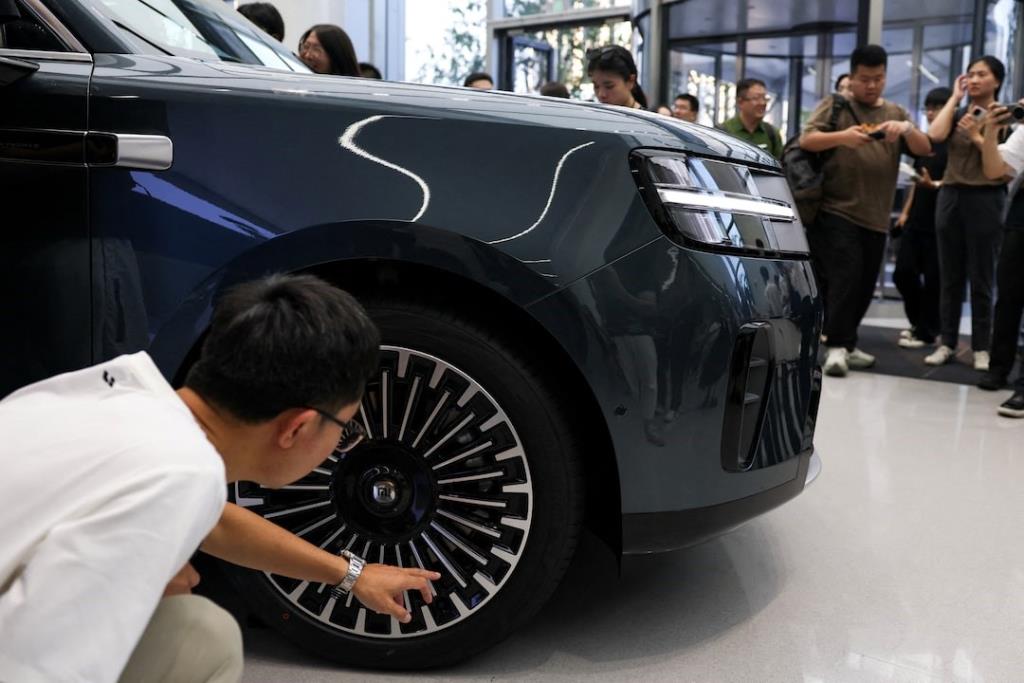 ชายคนหนึ่งกำลังตรวจสอบล้อยางของรถยนต์ SUV อัจฉริยะรุ่นเรือธงแบบ 7 ที่นั่งของค่ายเสียวหมี่ Xiaomi SkyNomad N90 Max EREV ซึ่งจัดแสดงก่อนงานเปิดตัวรถยนต์ ณ นิคมอุตสาหกรรมของเสียวหมี่ ในกรุงปักกิ่ง ประเทศจีน เมื่อวันที่ 30 กรกฎาคม 2569 – ภาพ : รอยเตอร์