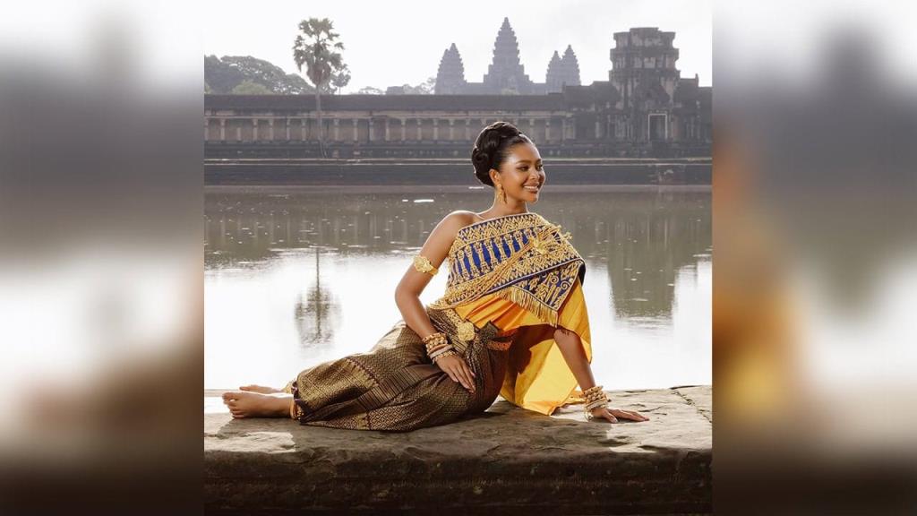 ภาพจากสมาคมนางงามกัมพูชา ที่มีคำบรรยายภาพระบุว่า กอย แอนนา ขณะสวมใส่สไบขแมร์ที่หน้าปราสาทนครวัด สถานที่ที่มีภาพแกะสลักเครื่องแต่งกายชนิดนี้ปรากฎให้เห็น.